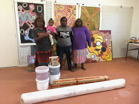 aboriginal artists posing for a photo near their artwork